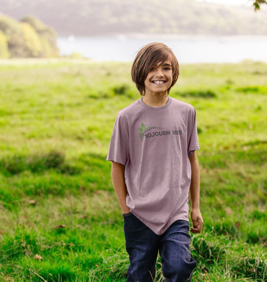 Youth wearing Sojourn Seed printed kids t-shirt in a field featuring a youth organic graphic t-shirt design