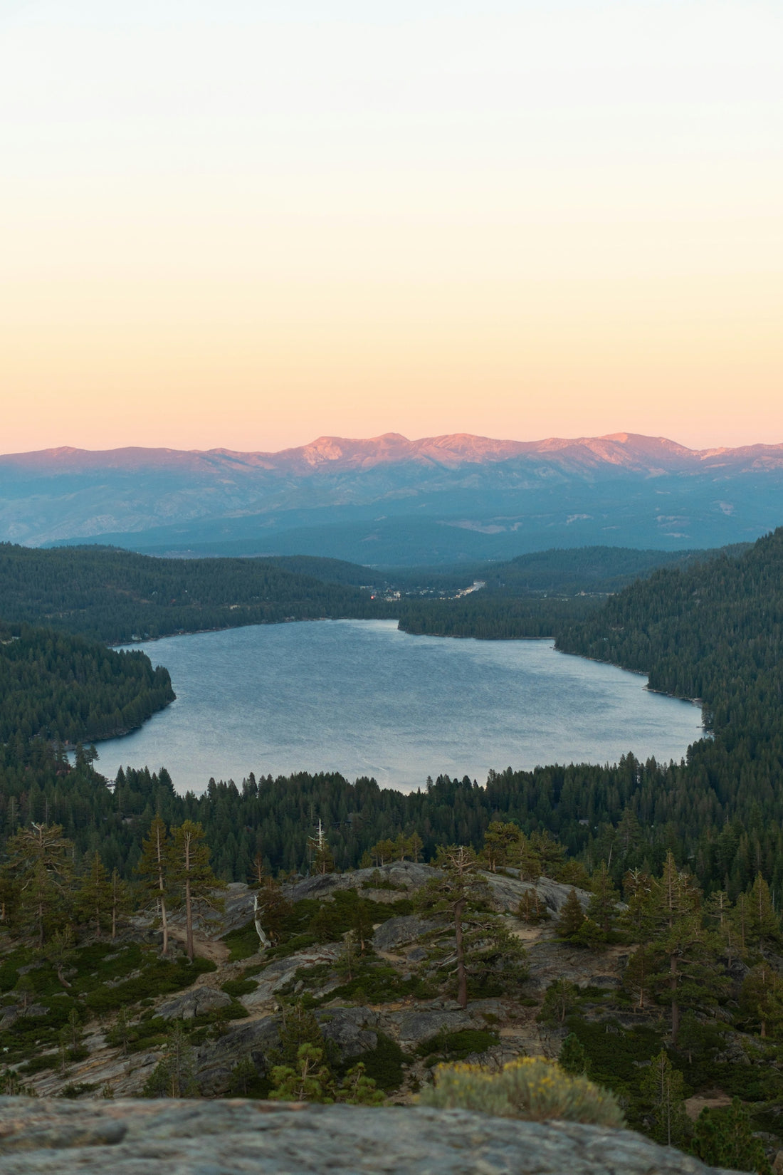 lake beside hill under cloudy sky