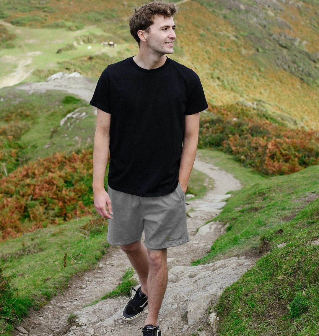 Man walking on trail wearing men's casual shorts and black t-shirt in outdoor nature setting