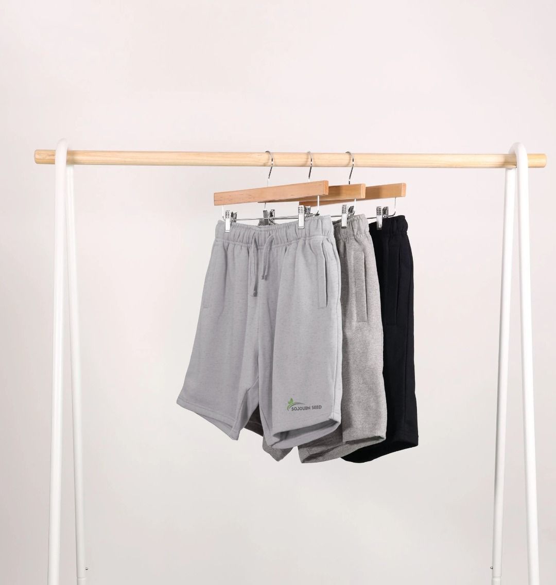Sojourn Seed printed men's casual shorts in gray, light gray, and black hanging on wooden hangers