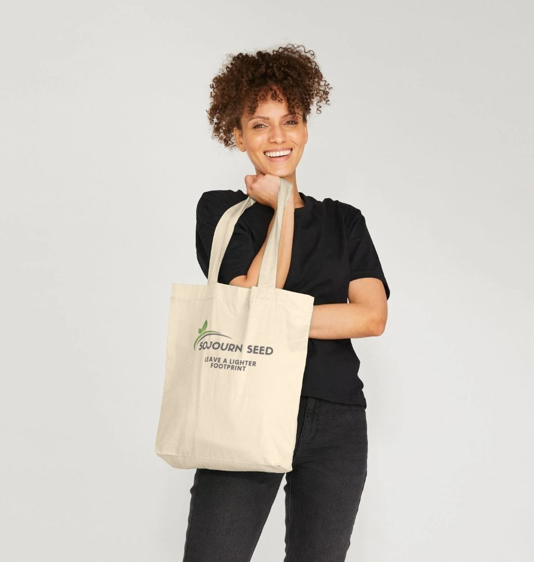 Sojourn Seed printed organic cotton tote bag held by smiling woman in black outfit