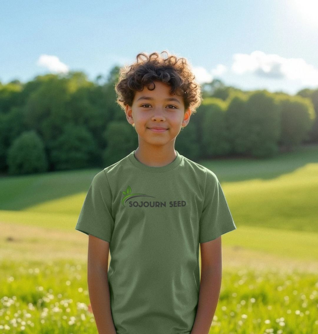 Youth wearing Sojourn Seed green youth organic graphic t-shirt standing outdoors in a sunny field